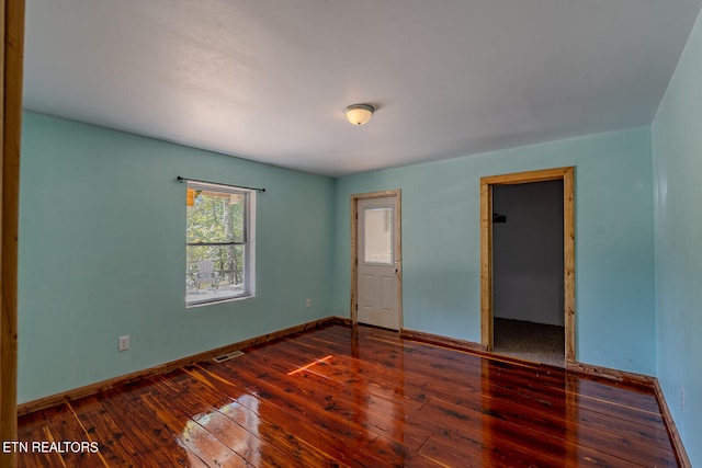 unfurnished bedroom with a walk in closet and dark hardwood / wood-style flooring