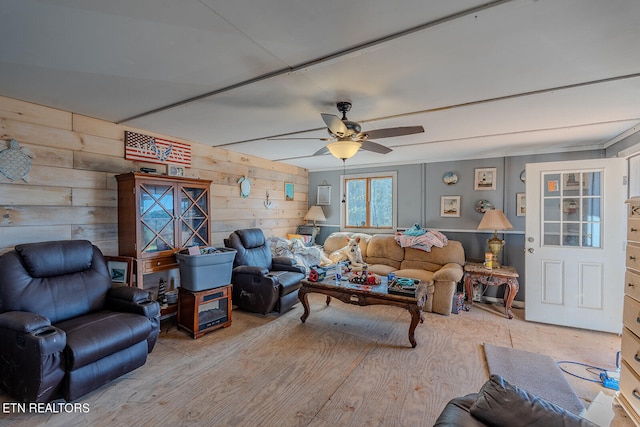 living room with light hardwood / wood-style floors, wooden walls, and ceiling fan