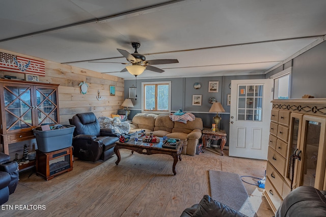 living room featuring ceiling fan, wood walls, and light hardwood / wood-style flooring