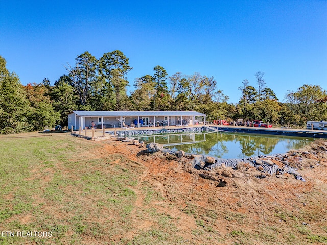 rear view of house featuring a water view and a yard