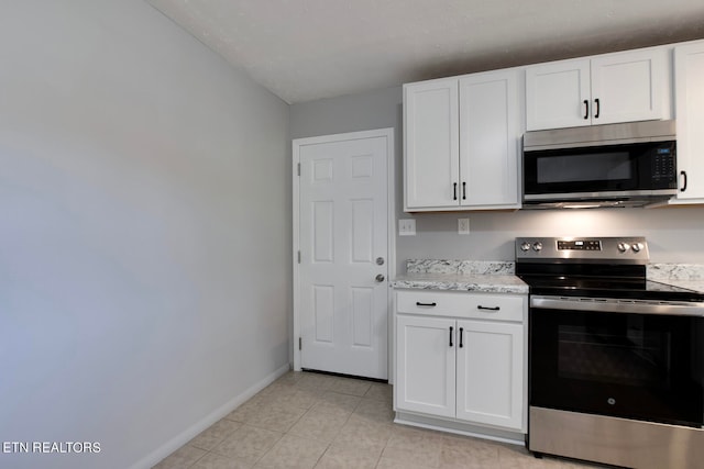 kitchen featuring appliances with stainless steel finishes, white cabinets, light stone countertops, and light tile patterned floors