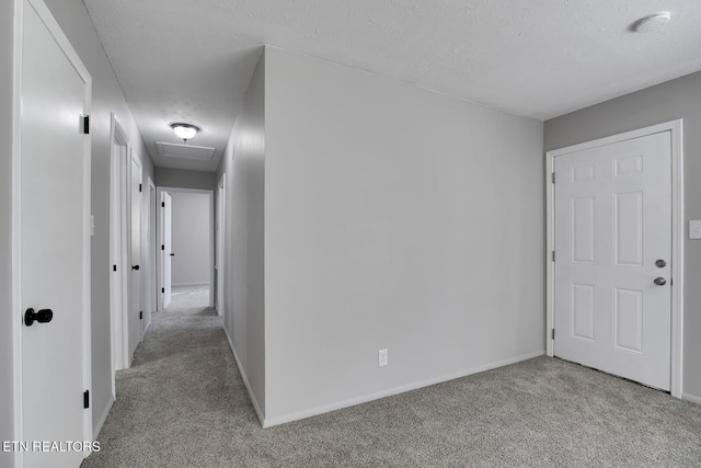 corridor featuring a textured ceiling and light colored carpet