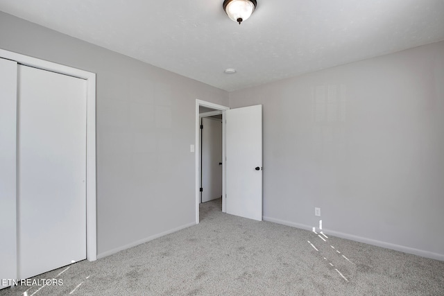 unfurnished bedroom with a closet and light colored carpet