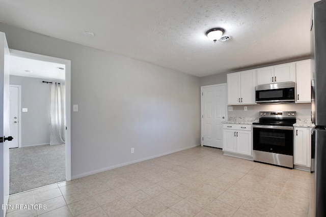 kitchen featuring white cabinets, light stone countertops, stainless steel appliances, and a textured ceiling