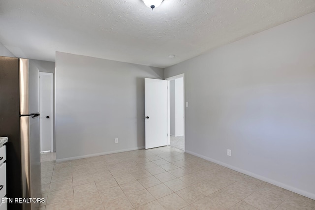 tiled empty room with a textured ceiling