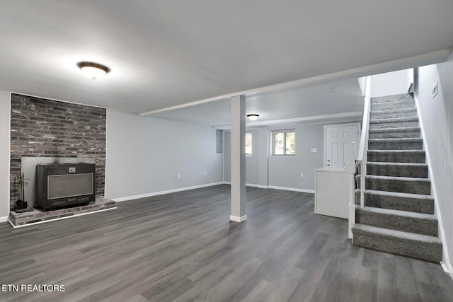 basement featuring a wood stove and dark wood-type flooring