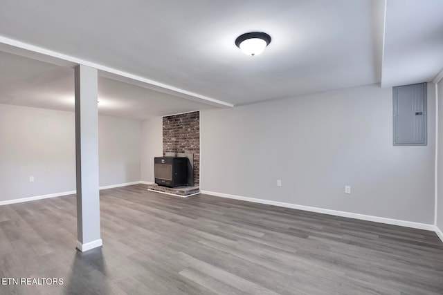 basement featuring a wood stove, hardwood / wood-style floors, and electric panel