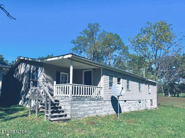 manufactured / mobile home featuring covered porch and a front lawn