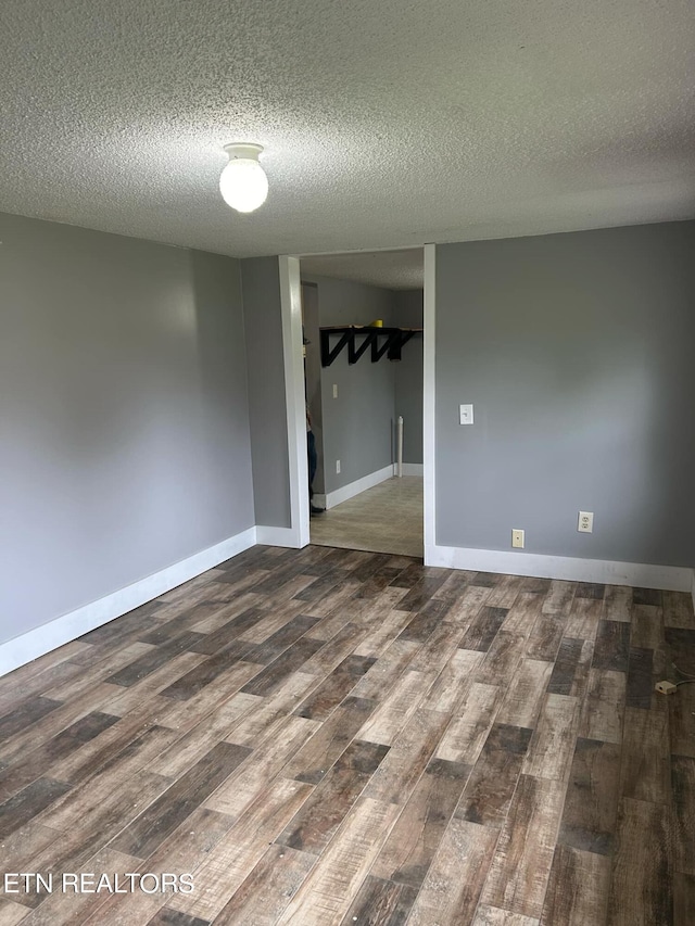 spare room featuring dark wood-type flooring and a textured ceiling