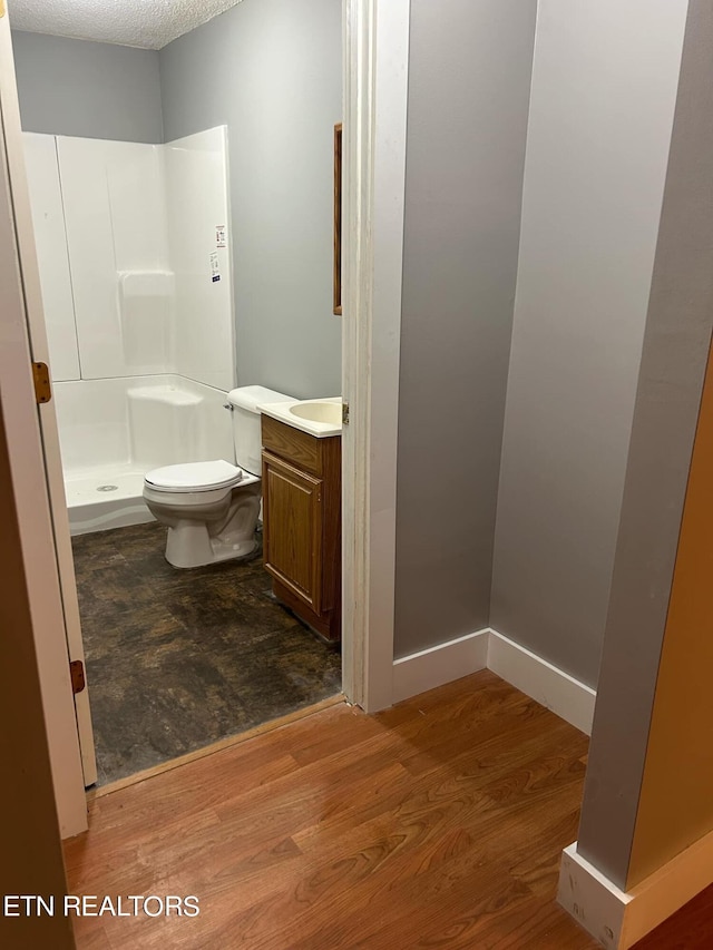 bathroom featuring a textured ceiling, walk in shower, wood-type flooring, toilet, and vanity