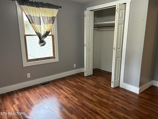 unfurnished bedroom featuring a closet and dark hardwood / wood-style flooring