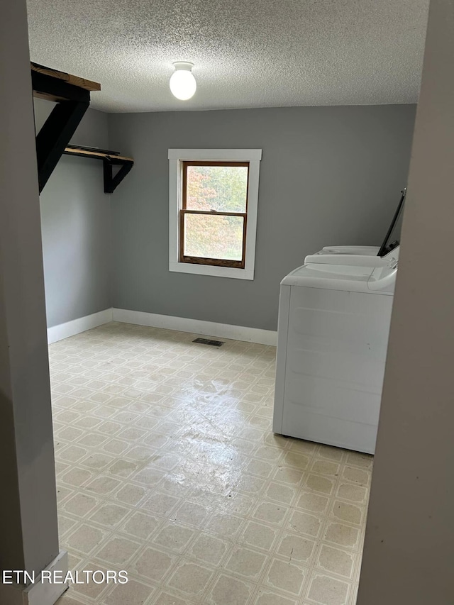 laundry room featuring a textured ceiling and washing machine and dryer