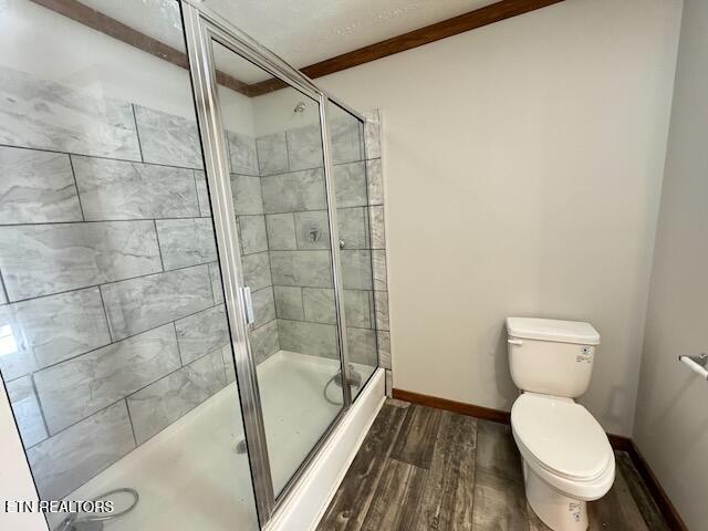 bathroom featuring a shower with shower door, wood-type flooring, and toilet