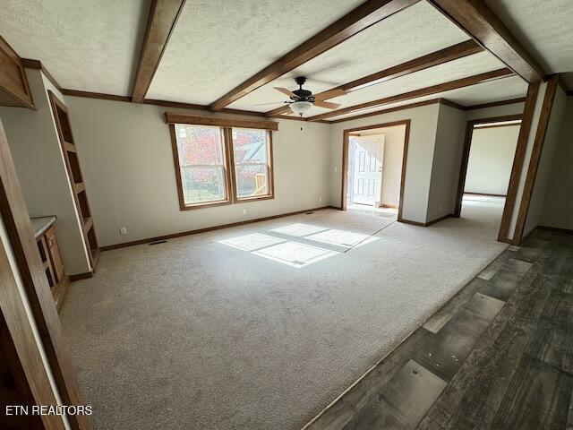 interior space with ceiling fan, a textured ceiling, carpet flooring, ornamental molding, and beamed ceiling