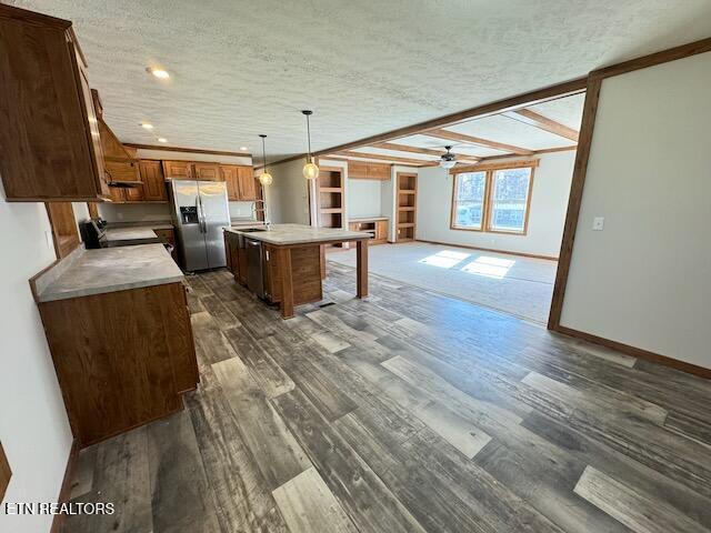 kitchen featuring a textured ceiling, decorative light fixtures, a kitchen island, and stainless steel fridge