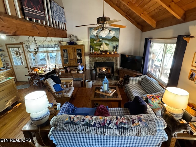 living room featuring wood ceiling, beamed ceiling, ceiling fan, a fireplace, and hardwood / wood-style floors