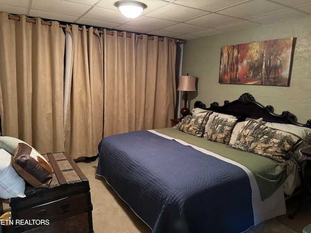 bedroom with light carpet and a paneled ceiling