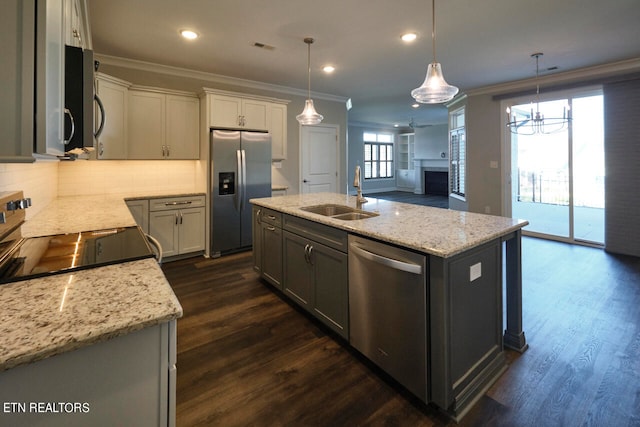 kitchen featuring pendant lighting, appliances with stainless steel finishes, sink, and an island with sink