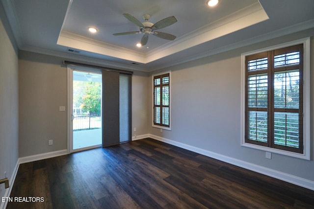 empty room featuring crown molding, ceiling fan, a tray ceiling, and dark hardwood / wood-style flooring