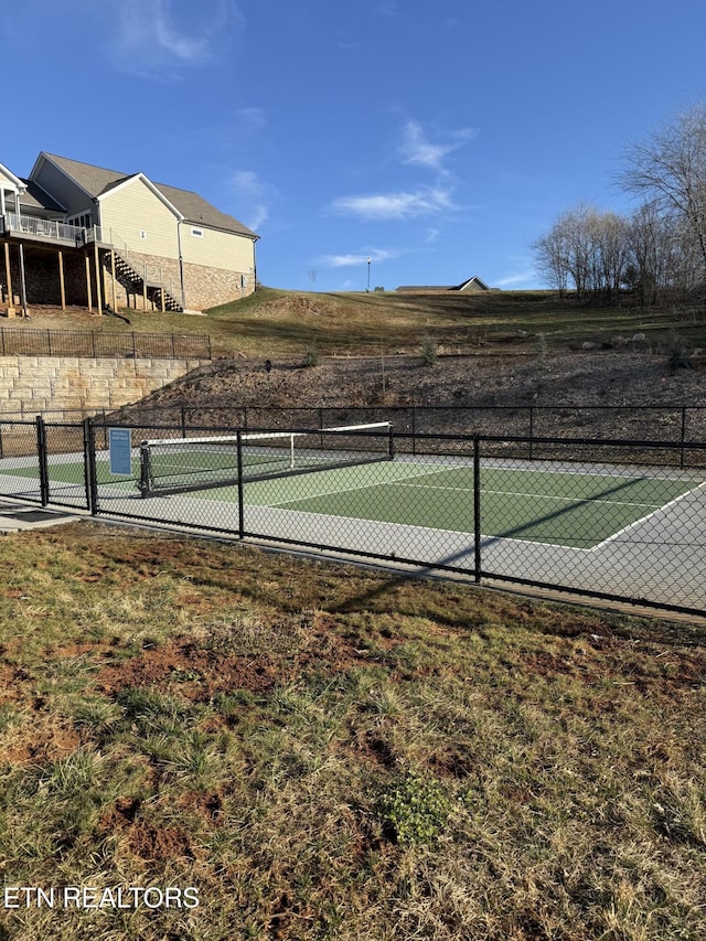 view of tennis court with stairs and fence