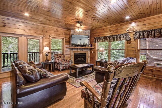 living area with a fireplace, wooden walls, hardwood / wood-style floors, ceiling fan, and recessed lighting