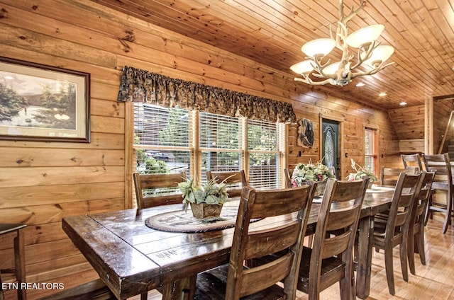 dining space with lofted ceiling, wooden ceiling, wood walls, a chandelier, and light wood-type flooring