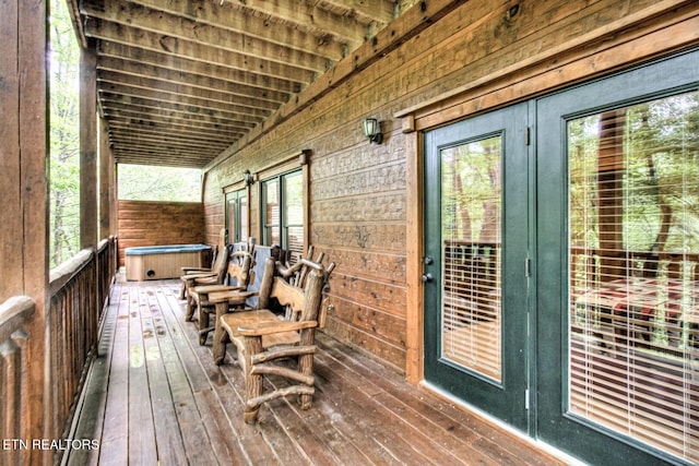 wooden deck with a hot tub and french doors