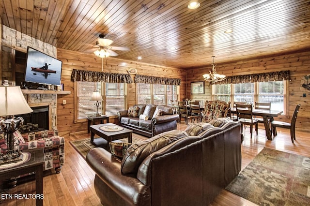 living room featuring wooden walls, ceiling fan with notable chandelier, wood ceiling, and hardwood / wood-style flooring