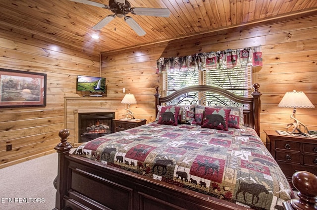 bedroom with wooden ceiling, wood walls, and carpet flooring