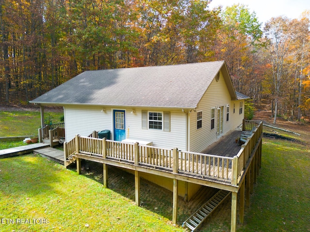 rear view of house featuring a wooden deck and a yard