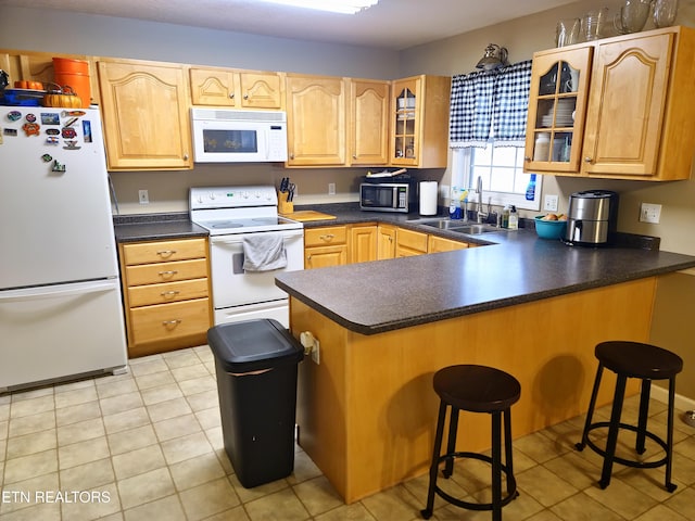 kitchen featuring kitchen peninsula, a breakfast bar, sink, and white appliances