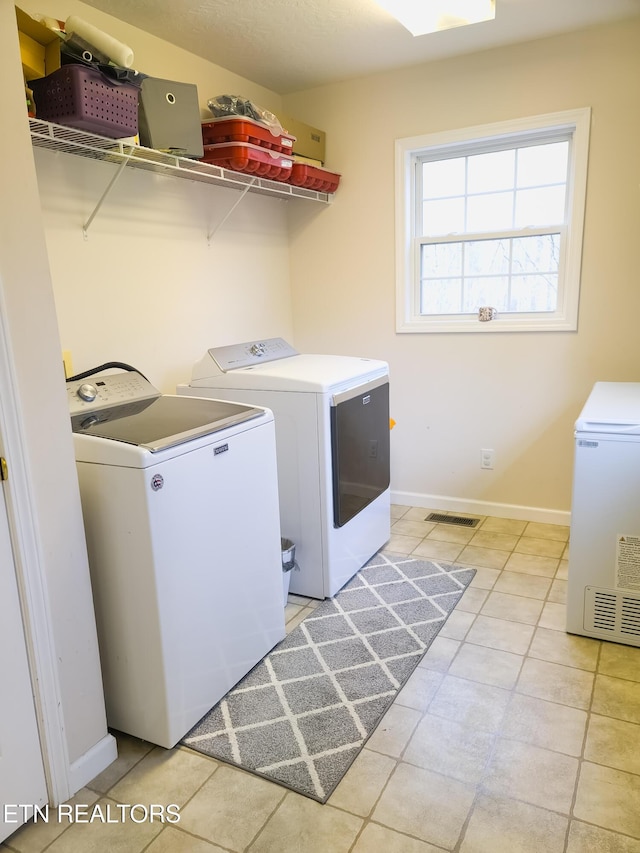 clothes washing area with washer and clothes dryer and light tile patterned floors