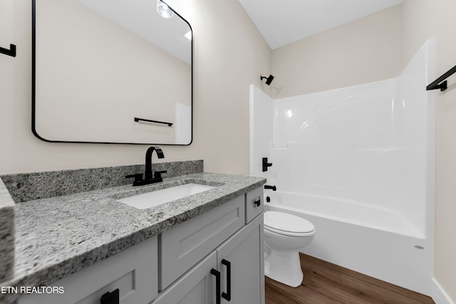 full bathroom with vanity, toilet, washtub / shower combination, and hardwood / wood-style floors