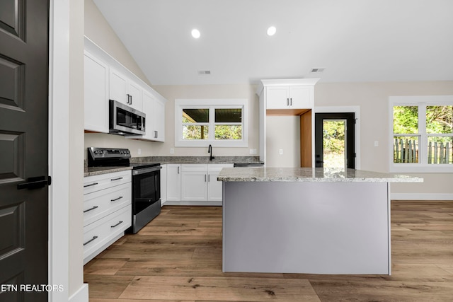 kitchen with lofted ceiling, white cabinets, stainless steel appliances, and plenty of natural light