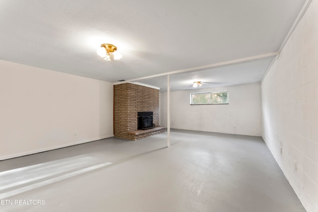 unfurnished living room featuring concrete flooring, a wood stove, and a textured ceiling