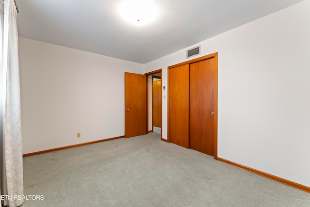 unfurnished bedroom with light carpet and a closet