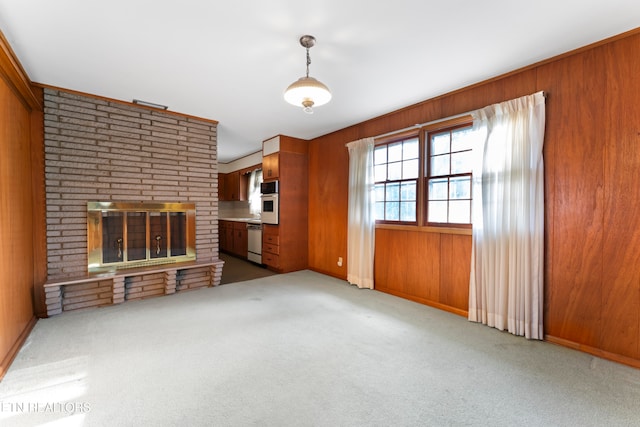 unfurnished living room featuring a fireplace, light colored carpet, and wooden walls