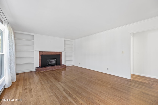 unfurnished living room with crown molding, built in features, and light wood-type flooring