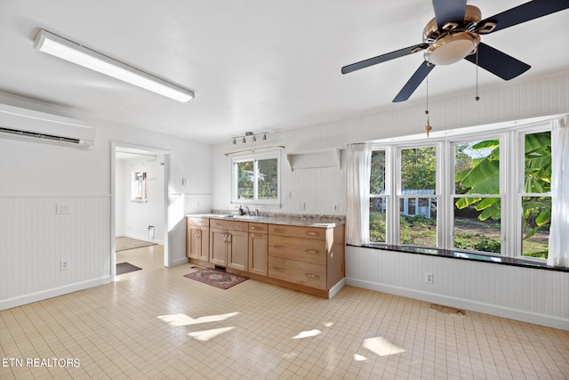 kitchen featuring wood walls, an AC wall unit, sink, and ceiling fan