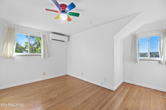 unfurnished room featuring ceiling fan, an AC wall unit, and light wood-type flooring