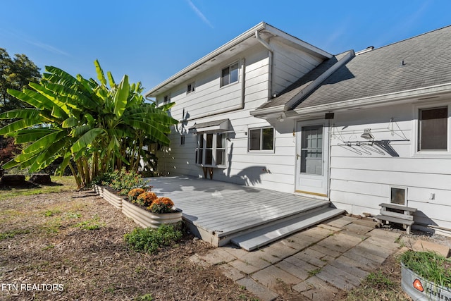 rear view of property featuring a wooden deck and a patio