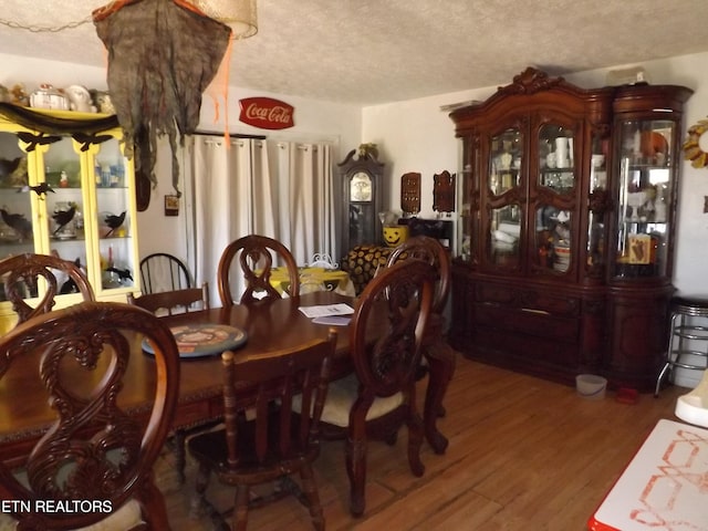 dining room featuring wood-type flooring and a textured ceiling