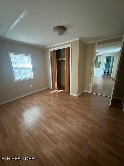 unfurnished bedroom with a closet, dark hardwood / wood-style flooring, and crown molding