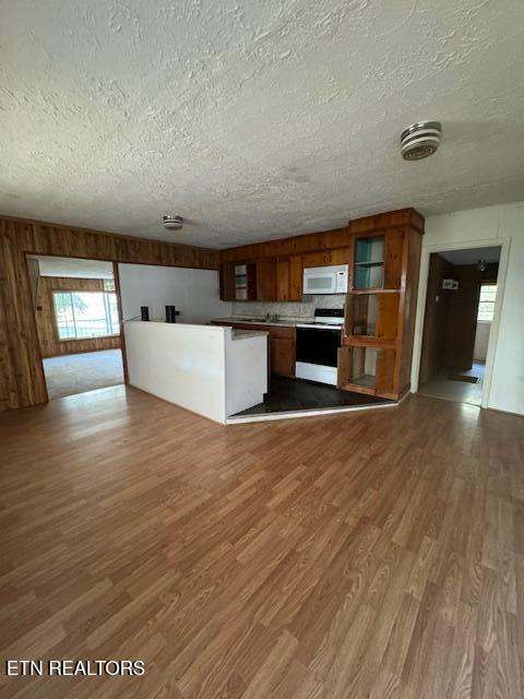 kitchen with a textured ceiling, decorative backsplash, hardwood / wood-style floors, and white appliances