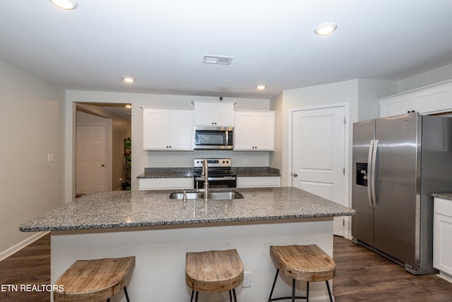 kitchen with sink, appliances with stainless steel finishes, a kitchen island with sink, and dark hardwood / wood-style floors