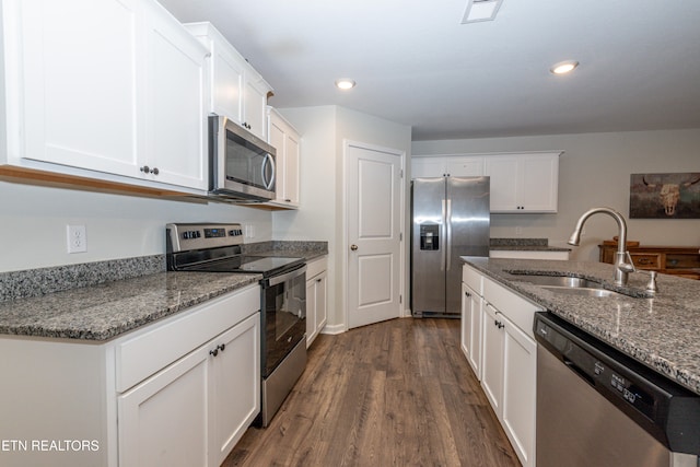 kitchen featuring appliances with stainless steel finishes, white cabinetry, dark hardwood / wood-style floors, stone countertops, and sink