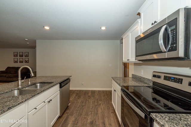 kitchen featuring dark wood-style floors, stainless steel appliances, white cabinets, a sink, and dark stone counters