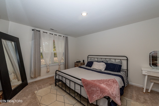 bedroom featuring baseboards, visible vents, and light colored carpet