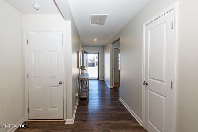 hallway with visible vents, dark wood finished floors, and baseboards