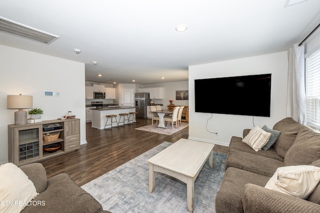 living room featuring baseboards, visible vents, dark wood-style flooring, and recessed lighting